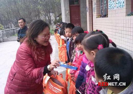 图：湖南省人大代表吴菊给孩子们发放学习用品。