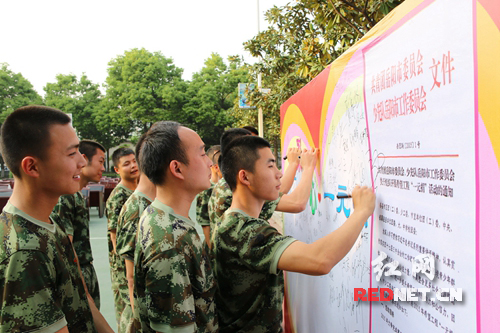驻岳公安现役部队官兵代表在“汇聚爱心”希望捐助主题背景墙上签名