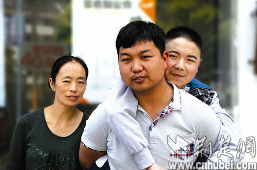 孙万龙背着罗红的孩子回家，一家人其乐融融。三峡晚报记者杜勇 摄