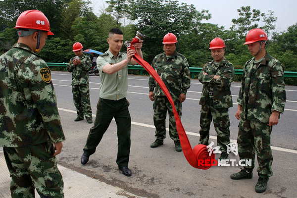 2015年5月13日，湖南省涟源市消防大队聂指导员在给桥头河镇消防队队员们演示如何使用收发消防水管