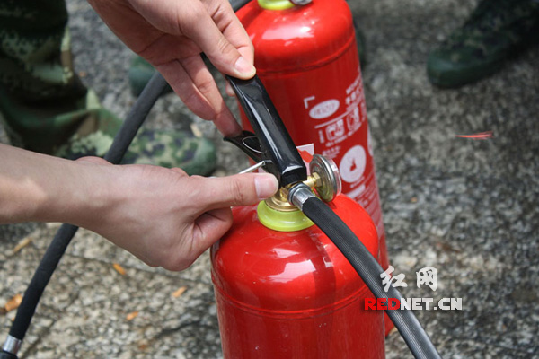 湖南省涟源市消防大队聂指导员在给桥头河镇消防队员演示如何使用灭火器。