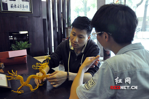 湖南网络工程职业学院大二学生曾向雄（右）向胡寅介绍自己的手工艺品——“中国龙”。