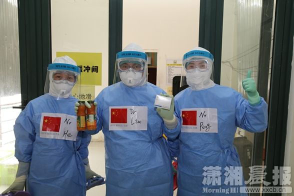 队员刘志勇、彭韵玲、何洁三人进隔离区给确诊的埃博拉患者做治疗，在中间的刘志勇拿着两瓶果汁和一盒药物，以增强患者体质2.JPG