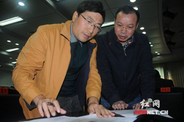张祖德[左]与娄底市国家税务局局长张诗东在重大税务案件审理现场查阅资料。
