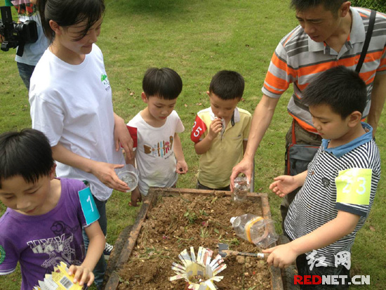 “地球绿伞计划”环保行动启动。图为小朋友和家长们正在用废饮料瓶做成绿色小花盆。
