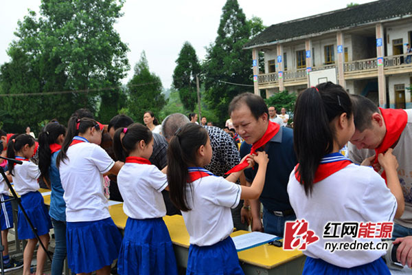 “六一”文艺汇演中留守儿童为“爱心爸爸妈妈”系红领巾