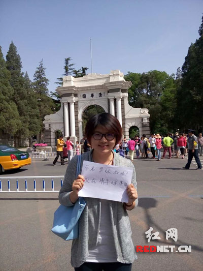湖南籍清华大学学子王瑶在清华二校门前举牌拍照，为家乡学弟学妹加油