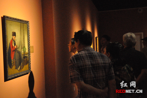 “19世纪欧洲古典写实油画欣赏”巡回展首站在谭国斌当代艺术馆开幕，爱好艺术的参观者们委屈着身子，仔细观看展览。