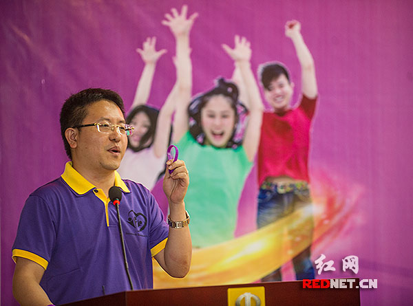 湖南青年心理协会秘书长孟奕爽先生手拿一只紫手环，讲述“不抱怨”的学术理念。