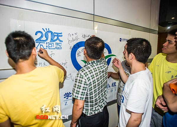 人们纷纷在活动现场“21天不抱怨”的背景板上签上自己的名字。