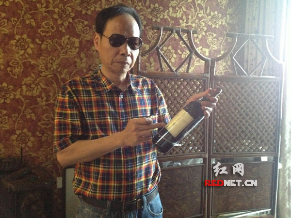 “湖南第一个食蟹人”刘兵展示他在购玖连锁店购买的无中文标识的“天价”红酒。