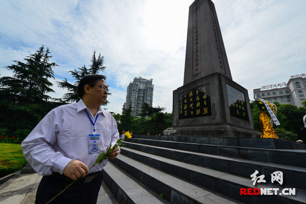 采访团成员手持黄花绕塔一周向阵亡将士致敬。