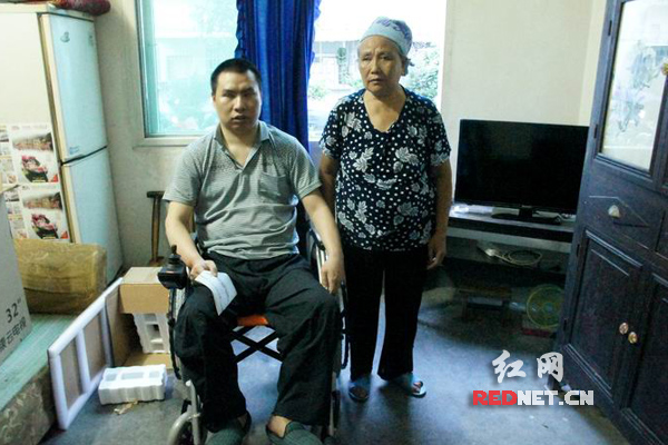 麻金德坐在轮椅上和老母亲开心的合影，身后是新送来的电视机