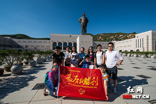 在延安革命纪念馆前，来自西安永明管理公司的游客们借《最后的胜利》旗帜合影，他们称这一主题很切合参观感受。