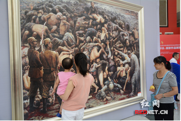 展览展出了李自健的油画《南京大屠杀》，图为一名母亲怀抱小孩在观看油画。