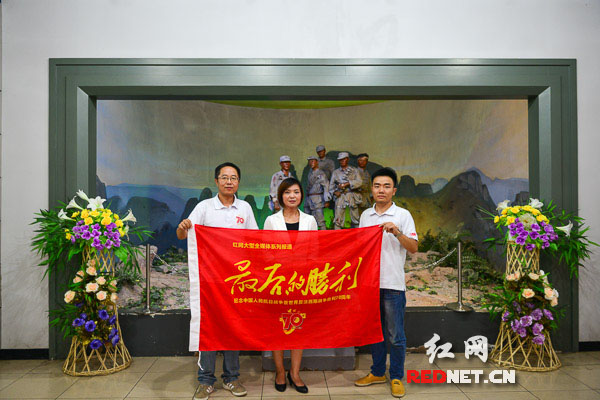 狼牙山纪念馆馆长李芳接受记者采访并与记者共同举起“最后的胜利”旗帜