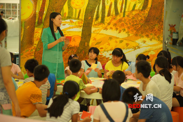 湖南留守儿童在广州图书馆老师的指导下制做绘本。摄影：郑纪军