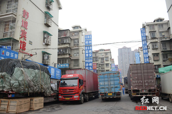 物流市场内，货物遍地堆，大型货车无序停放在道路上，火灾隐患大