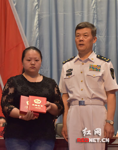海军副政委丁海春向梅雄爱人颁发勋章、证书。