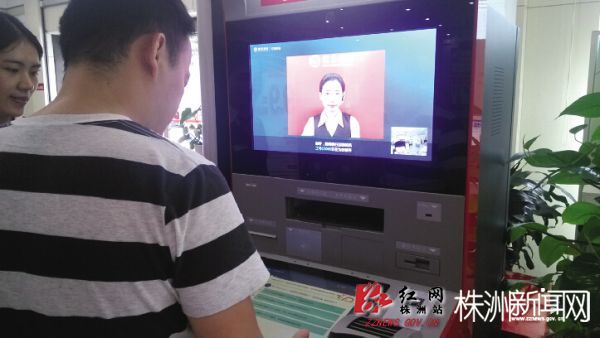 图为市民在银行工作人员指导下，利用VTM机办理业务。（记者 陈正明 摄）