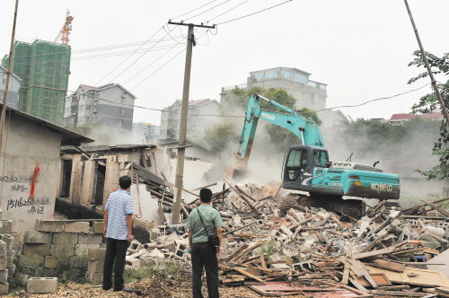 昨日上午，在猴子石大桥西北角，岳麓街道城管工作人员正在对一处违章建筑群进行拆除。 长沙晚报记者 邹麟 摄 