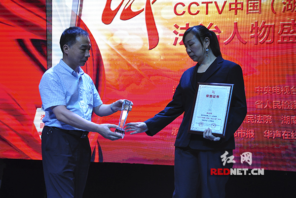 湖南省人民检察院检察委员会专职委员丁维群为陈运周妻子刘小英颁奖。
