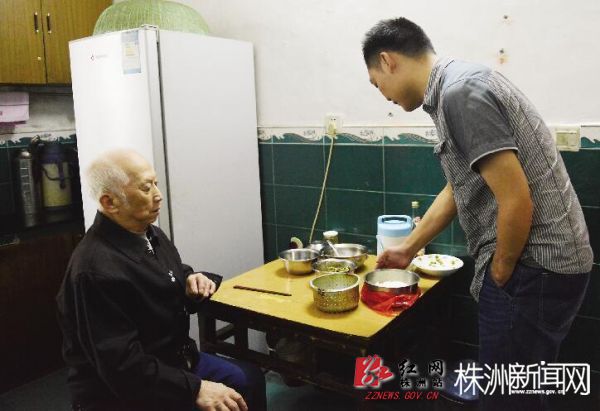 井墈社区工作人员上门给老人送饭,并陪老人聊天。(记者 谢慧 摄)