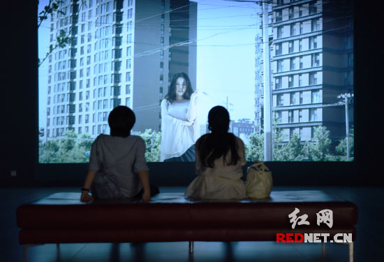 艺术家用投影仪展示的艺术作品让两个女生看得很入迷。