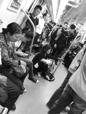 女子抱着孩子坐在地上,无人让座
