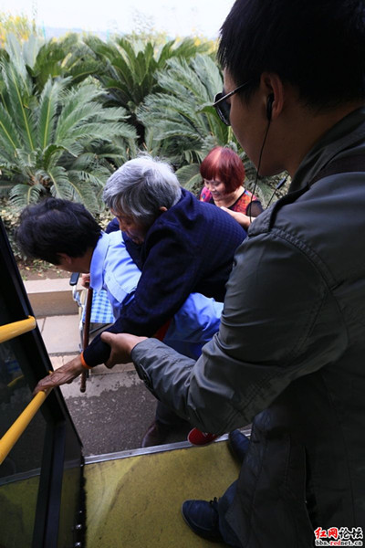 颜师傅背着老人，可老人还是不放心吃力的抓着车把手不肯放手，弄的司机好狼狈 网友供图。