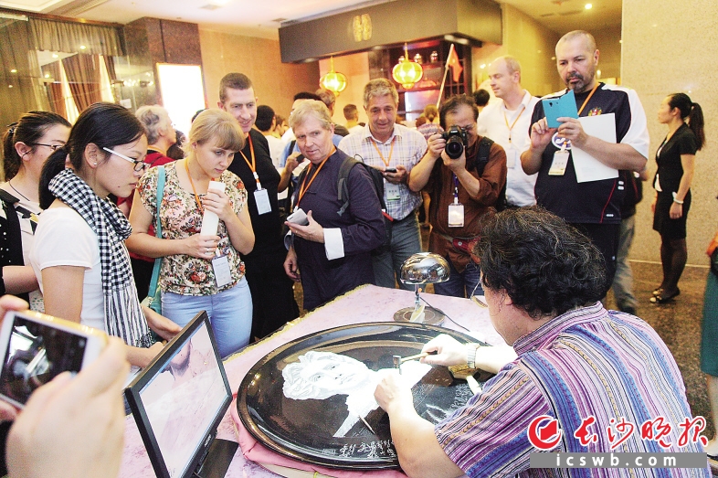 　　↑昨日，在秦皇食府，外国朋友对长沙特色的手工艺作品表现出浓厚的兴趣。