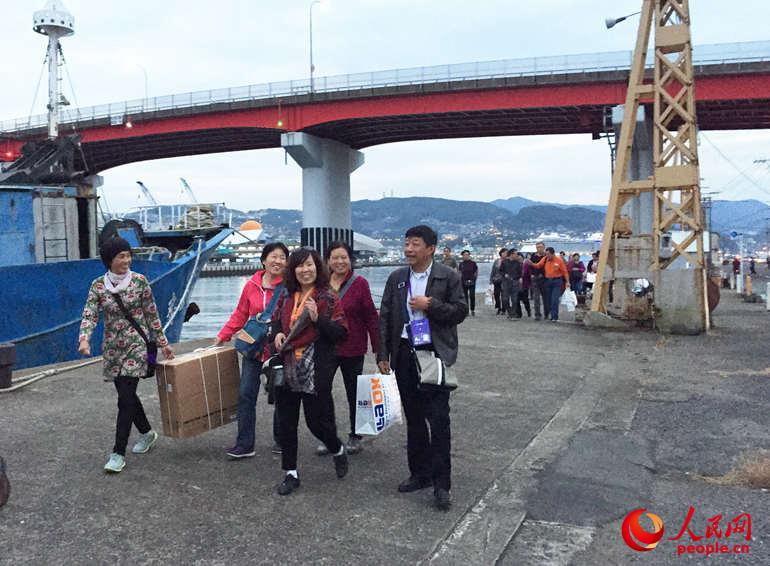 一位来自中国游客在日本免税店买了一个马桶盖，朋友帮忙提着返回旅游大巴。 人民网 冯亚涛 摄