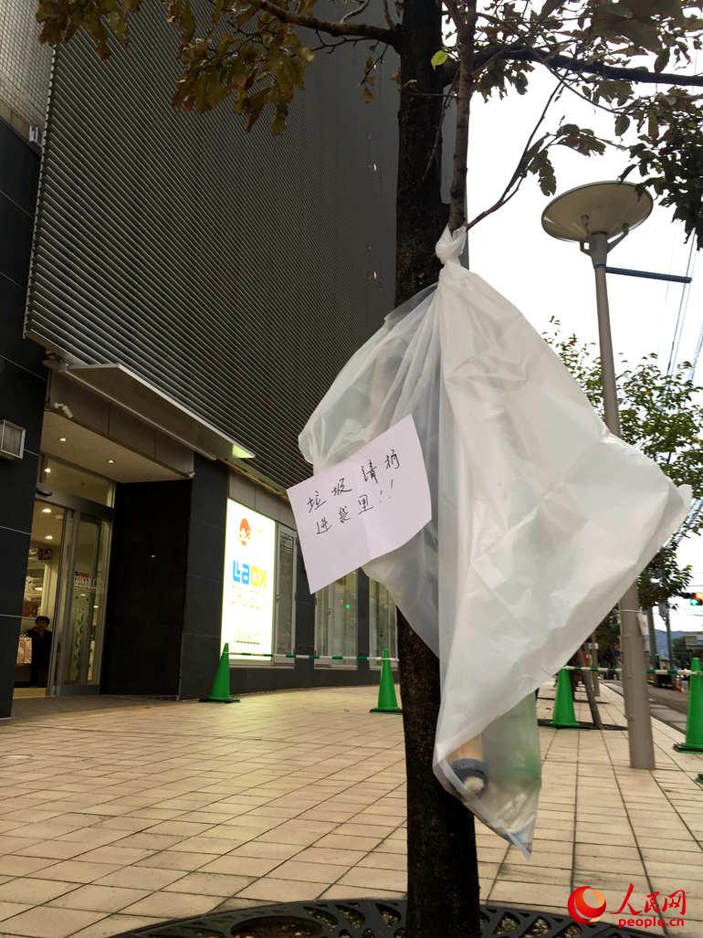 日本施行严格的垃圾分类，且大街上基本上没有垃圾桶。为了迎合中国游客，免税店将一个白色的垃圾袋专门放在门口，供游客扔垃圾，之后免税店再统一分类。 人民网 冯亚涛 摄