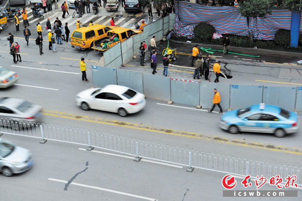 昨日下午，南湖大市场北侧一路段路面塌陷一平方米左右的坑洞，市政人员架起围挡进行勘测处理。 长沙晚报记者 余劭劼 摄
