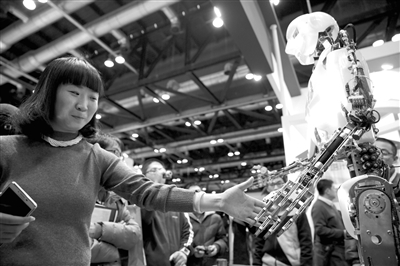 2015世界机器人大会于11月23日至25日在北京国家会议中心举行。图为一位参观者在同机器人握手。记者 金立旺 摄