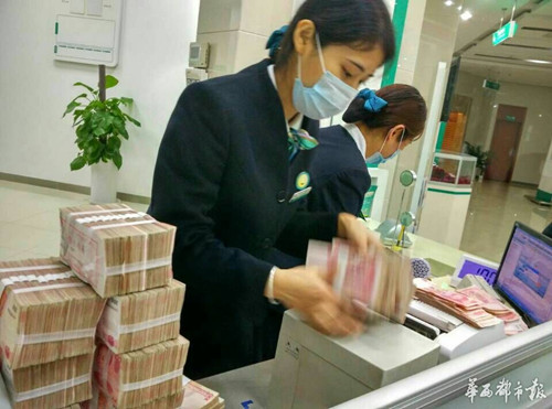 银行工作人员戴着口罩清理发霉的钱。