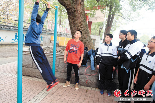 长沙市21中体育教师张毅夫（红衣者）正在指导学生做引体向上。　　长沙晚报通讯员 黄军山摄