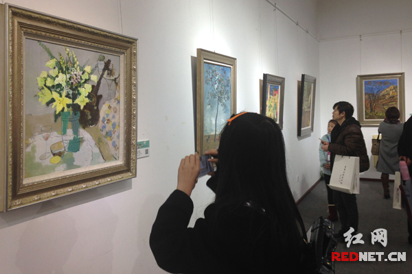 爱好艺术的参观者，站在展出油画作品前细细揣摩其中的神韵。