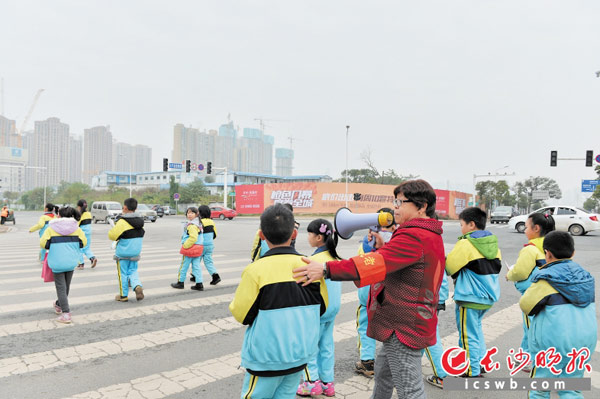 在滨江小学校门口，帮帮团成员张利纯每天为学生们护航，保障学生们过马路的安全。