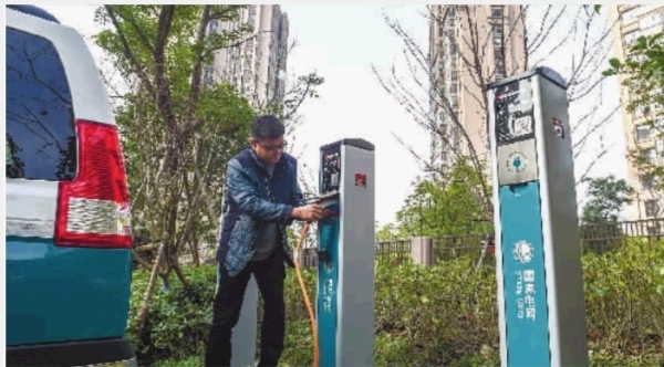 12月27日,长沙市政府大楼前杜鹃广场南面,市民正在为新能源汽车充电。