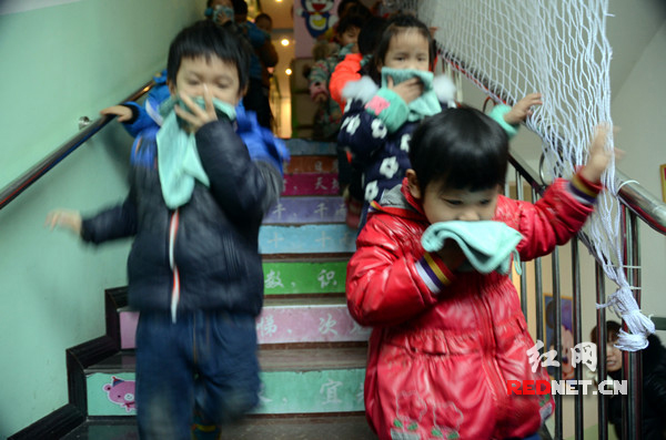孩子们一个个弯着腰从各个班级井然有序地从消防通道口迅速撤离“火灾”现场