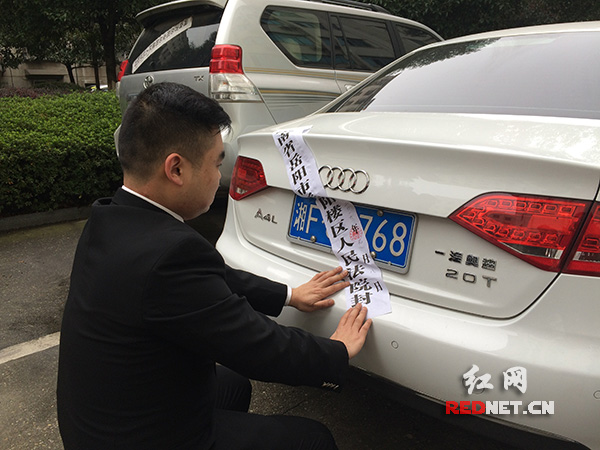 岳阳市楼区法院执行局法官给“老赖”的车贴上封条。