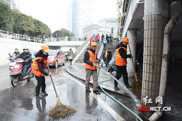 长沙芙蓉广场西南角，3名环卫工人正在用水清刷道路。