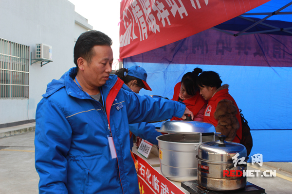 中石化湖南省郴州分公司临武片区隆武加油站站长陈建雄在查看煮的热食是否还充裕。