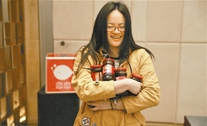 员工高兴地领取老干妈、充气娃娃等年终奖品。 