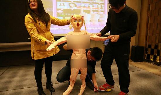 员工高兴地领取老干妈、充气娃娃等年终奖品。 