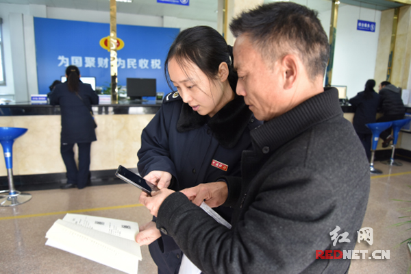 韶山地税大厅工作人员指导纳税人扫描二维码，了解办税事项。