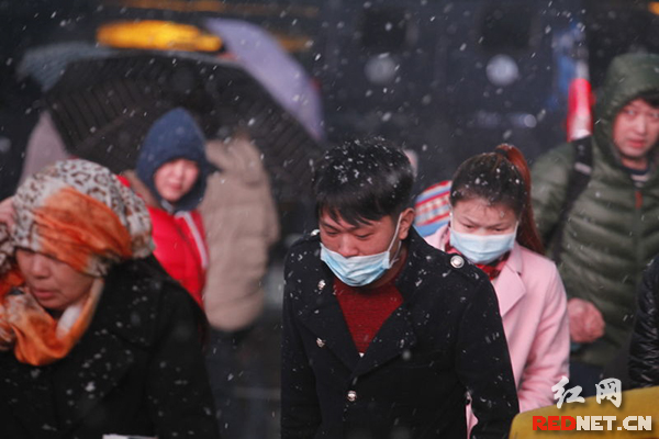 1月31日,长沙火车站,市民冒雪前行。