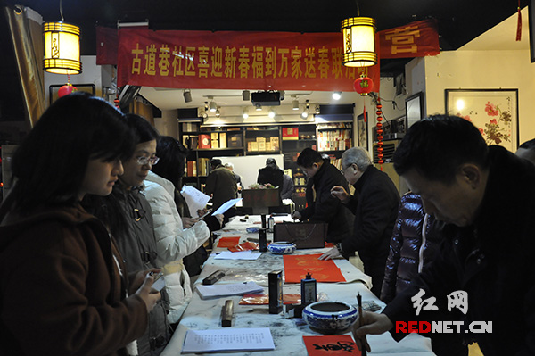 湖南省政法系统书画诗词研究会近十位书法爱好者汇聚俱和老茶楼，现场手写喜气春联，为长沙天心区古道巷社区居民送去新春的问候和祝福。