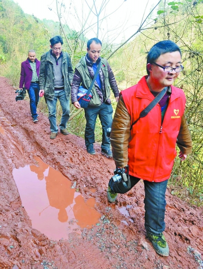2月9日，湖南日报摄影师行走在泥泞的简易公路上，前往沙坪组为村民拍摄“全家福” 。湖南日报记者 李健 童迪 摄影报道
